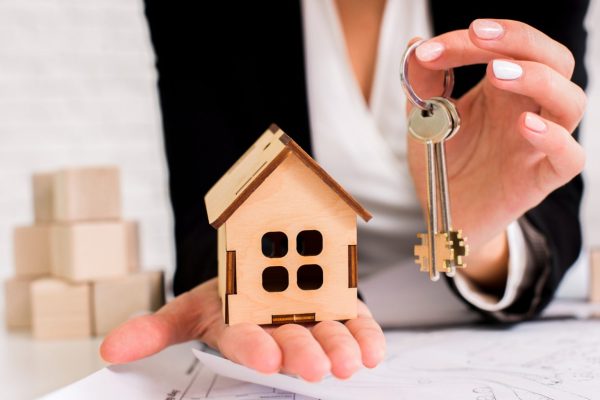 woman-holding-set-keys-with-wooden-house-1536x1025